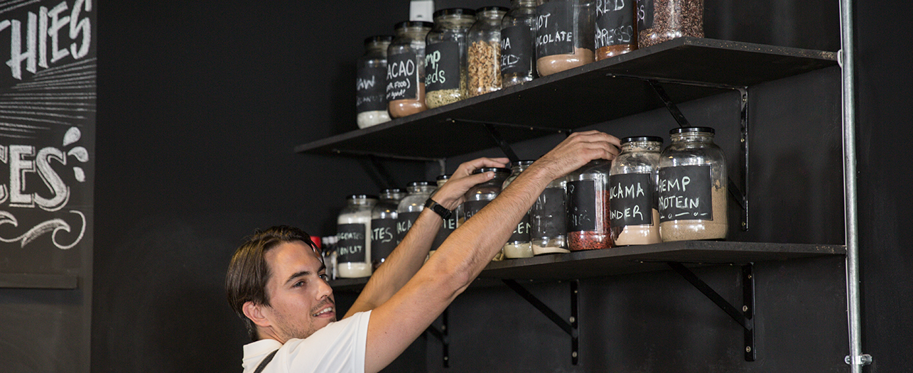 Cafe worker organizing ingredient jars on the shelf