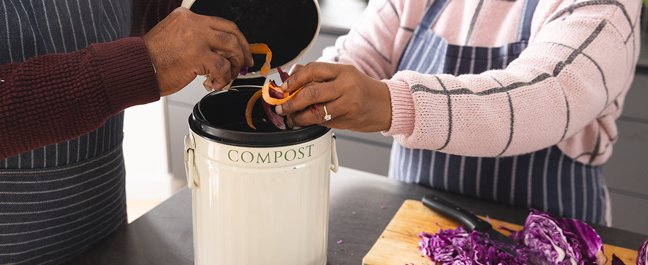 People adding vegetable scraps to the kitchen compost bin