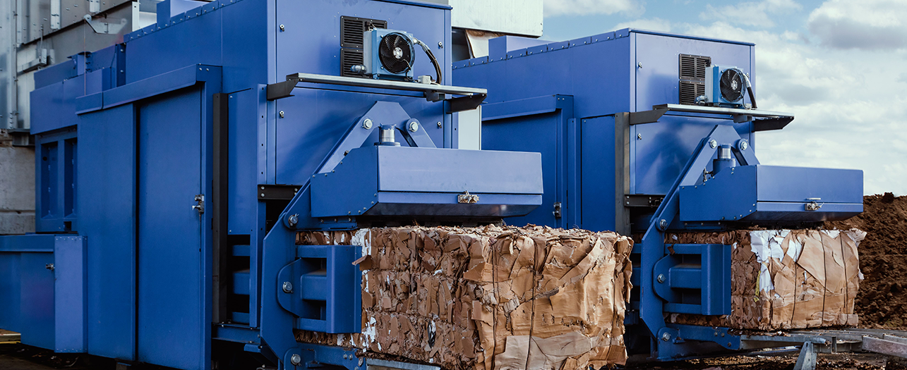 Industrial waste baler compressing cardboard at a recycling facility