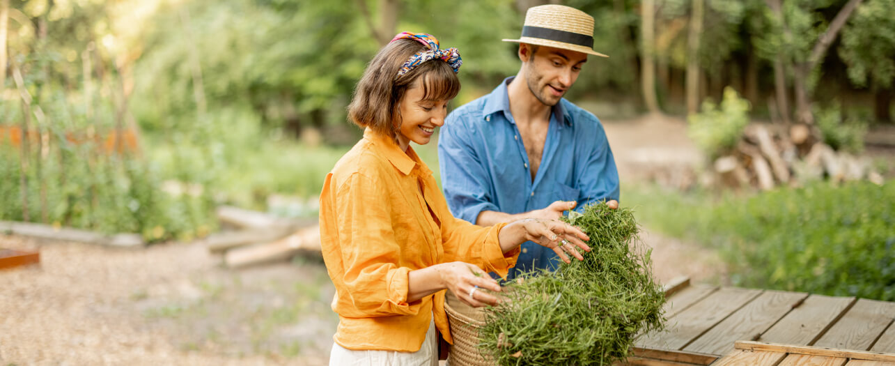 Couple throwing grass to compost wooden garbage bin