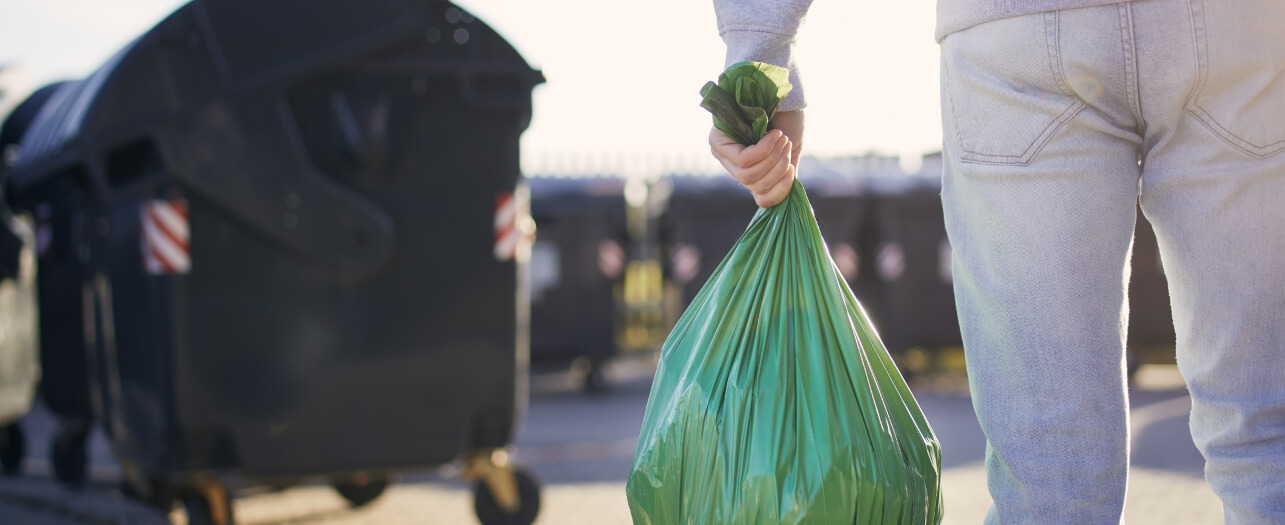 Man carrying garbage bag towards the waste skip