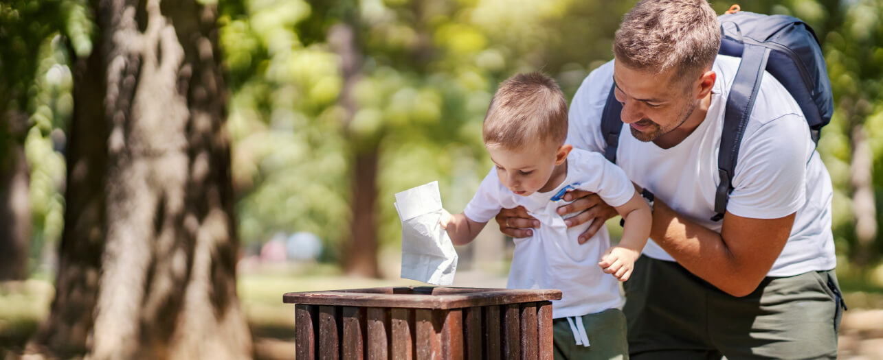 Father and son throwing trash in the waste bin