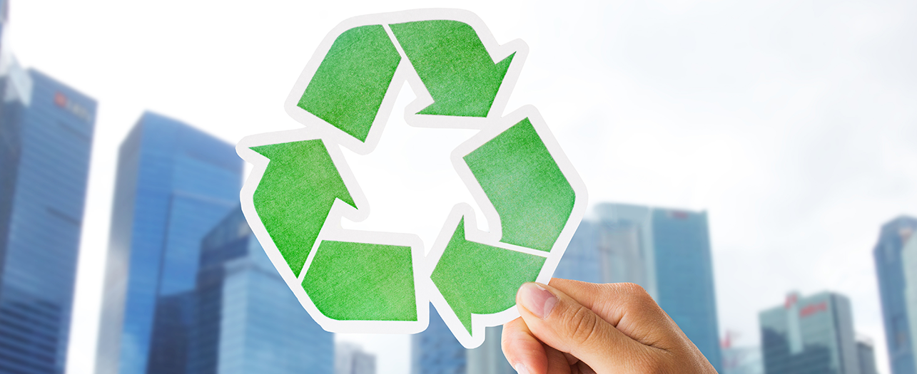 Recycling symbol held up against city skyline Image 2 - The Economic Benefits of Recycling for Businesses.png
